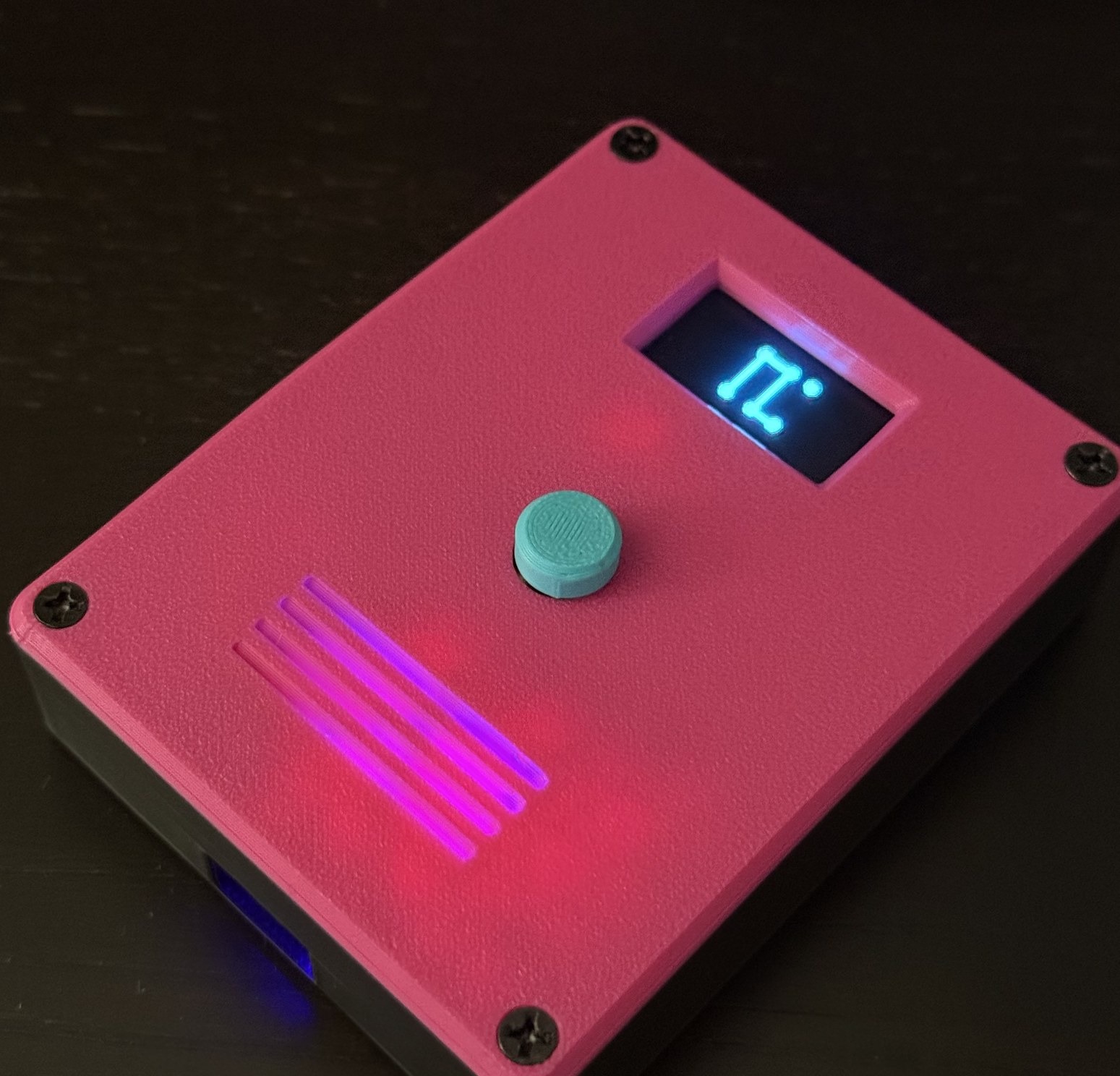 A finished badge in a dark room, screen lit, the grille and the USB port glowing